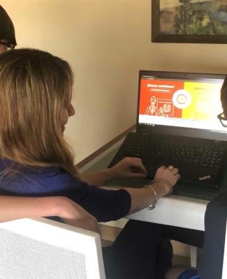Imagen de María ante el ordenador rodeada de sus hijos 