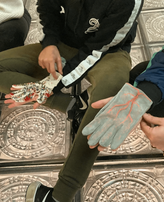 Foto en la que aparecen dos personas con dos guantes diferentes hechos a mano 