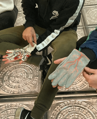 Foto en la que aparecen dos personas con dos guantes diferentes hechos a mano 