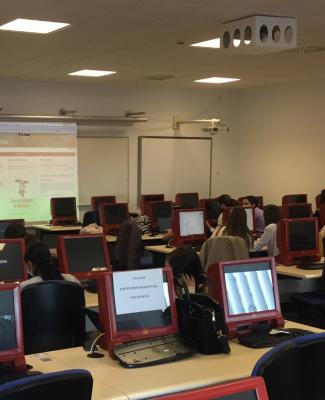 Imagen de un aula en la que se ven pantallas en los pupitres