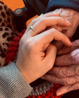 Imagen de una mano sobre las manos de una persona mayor 